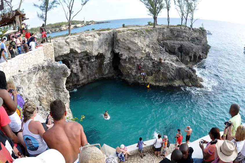 Cliff diver jumping into the Caribbean Sea at Rick's Cafe Negril Jamaica