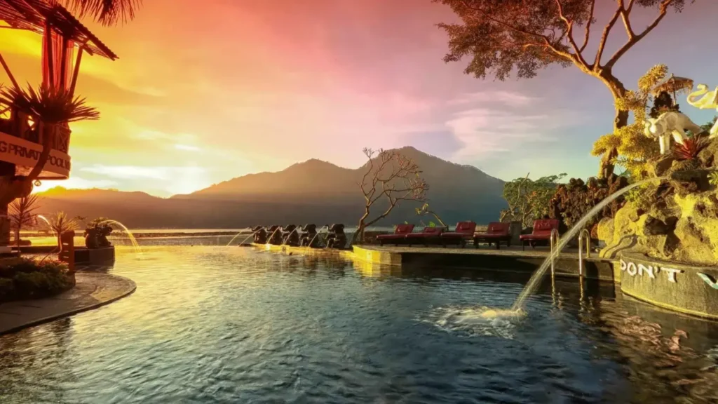 Mount Batur sunrise volcano trek in Bali with dramatic sky, clouds and hikers on mountain summit during golden sunrise